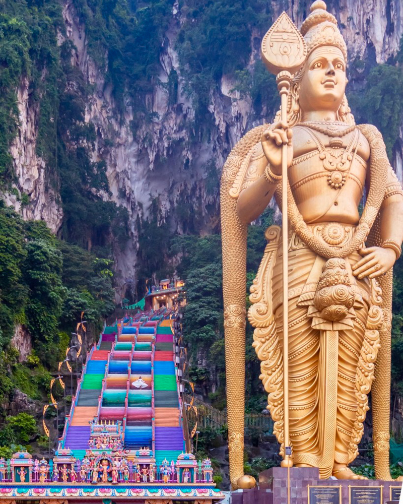 A girl in white dress standing at the colorful stairs at Batu Caves