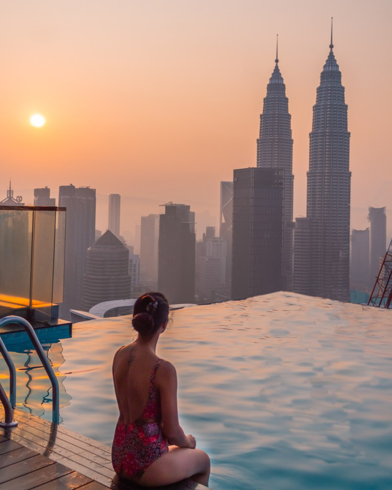 A girl in swimsuit sitting close to the infinity pool at face suites