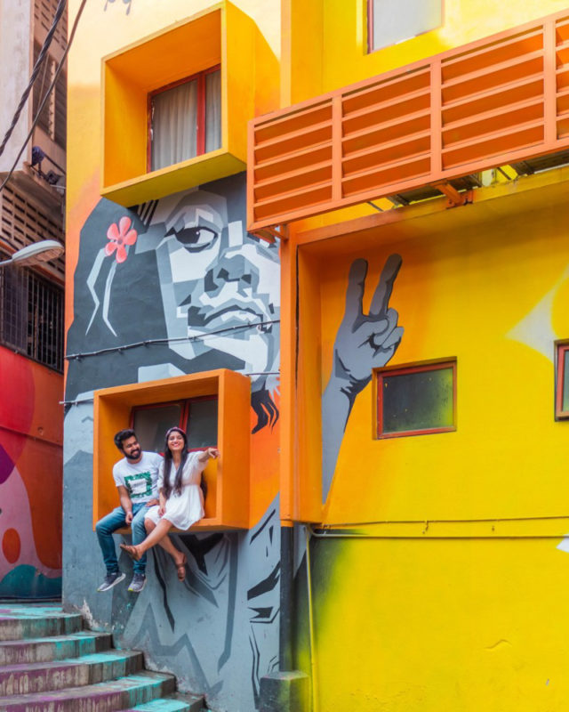 A couple sitting in an area of Bukit bintang street with colorful murals