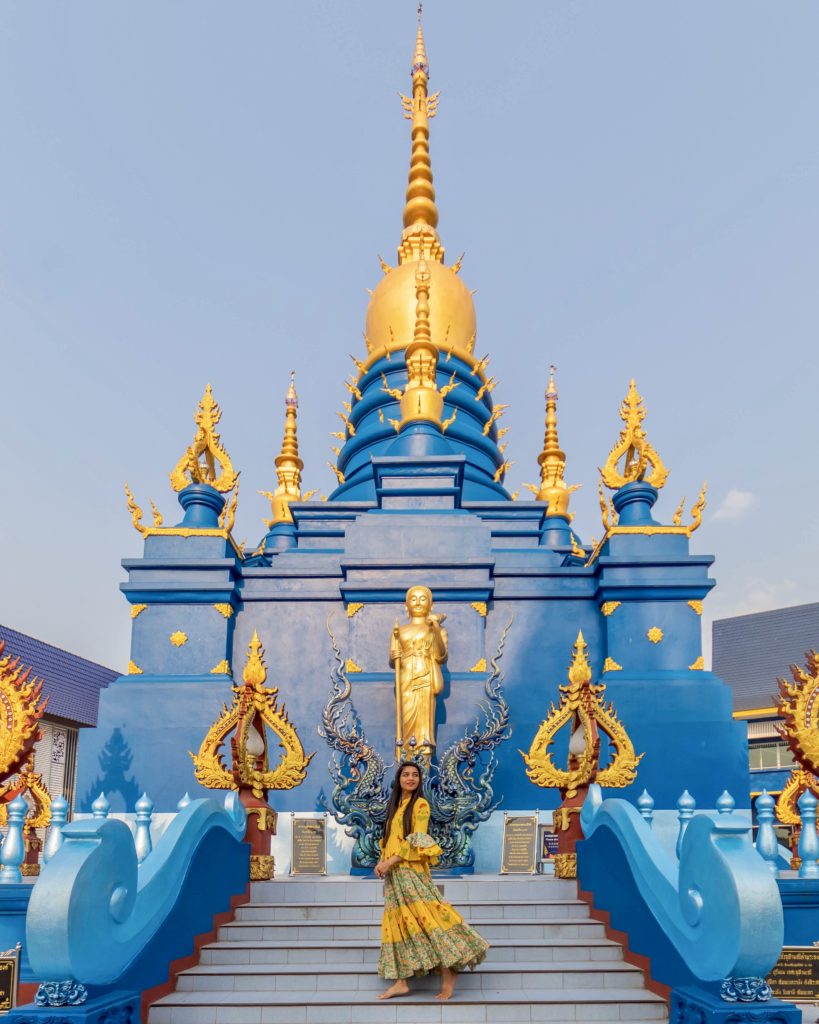 A girl standing at the back of blue temple posing in yellow