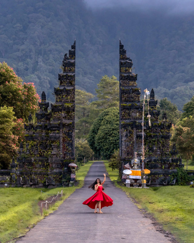 A girl in red dress posing at handara gate in munduk north bali