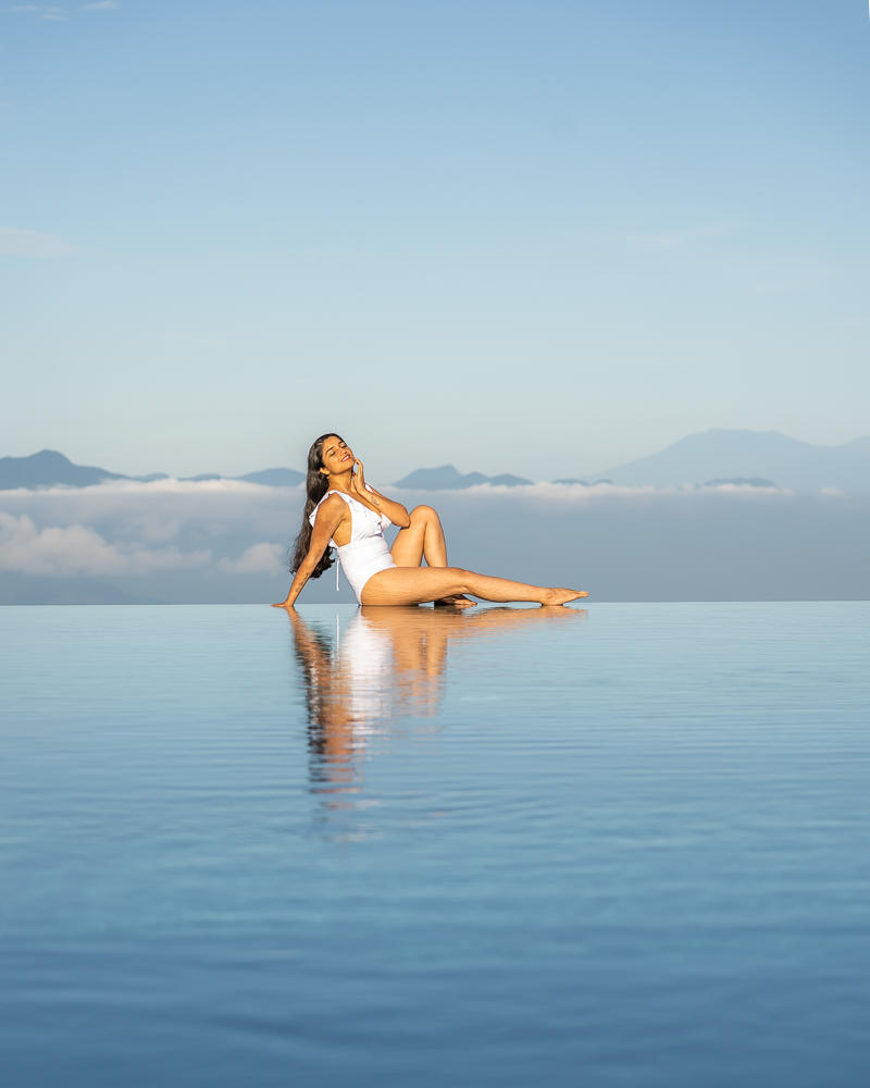 A girl in white swimsuit posing at munduk moding resorts infinity pool in munduk bali