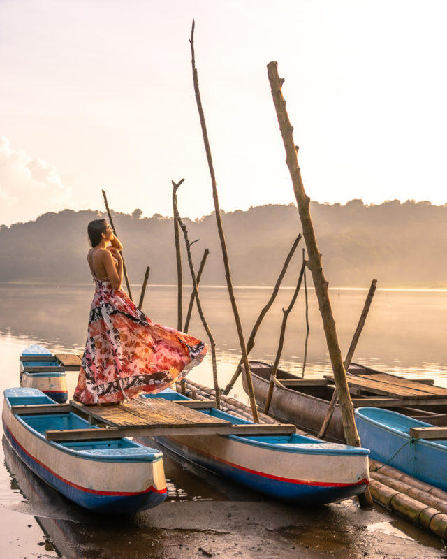 A girl in a dress posing on a canoe at Lake Tamblingan in Munduk north bali