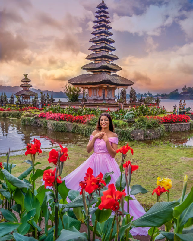 A girl in pink dress in front of flowers at Ulun Danu Bratan temple in Munduk bali