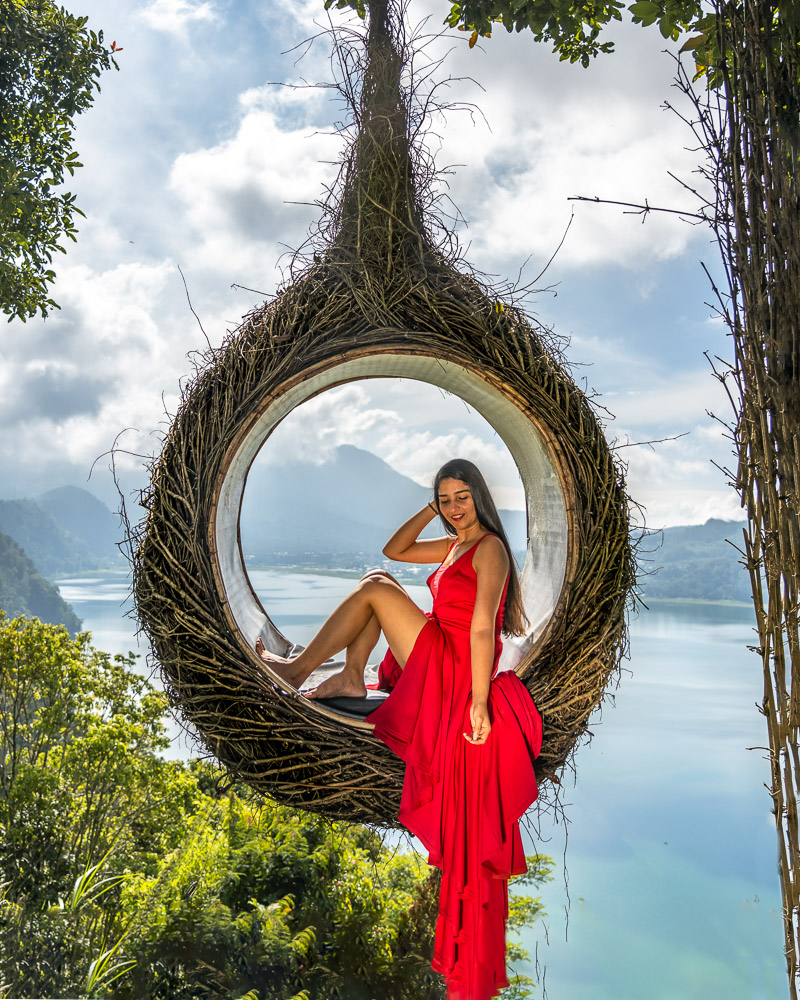 A girl in red dress sitting in a nest installation at wanagiri hidden hills in munduk bali