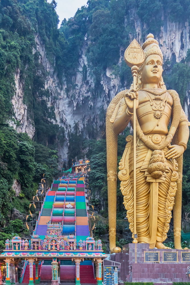 A girl in white dress twirling on colorful stairs at batu caves during 3 day Kuala Lumpur itinerary