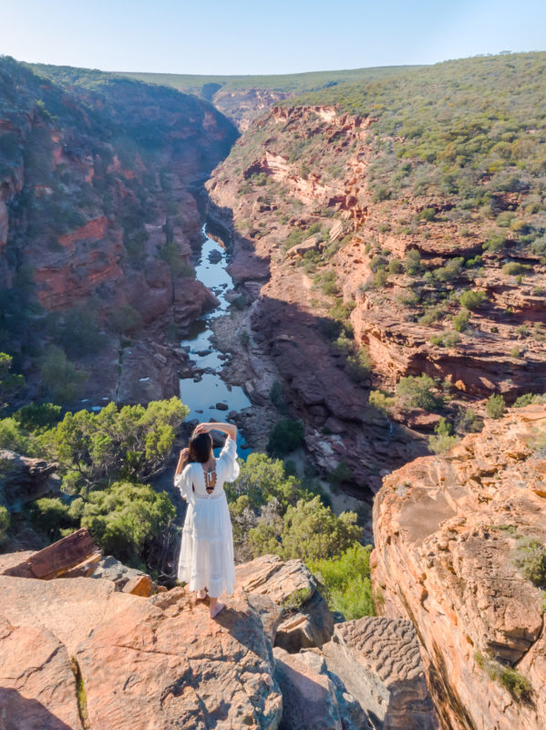 A girl in a white dress standing at the lookout of Z bend river trail
