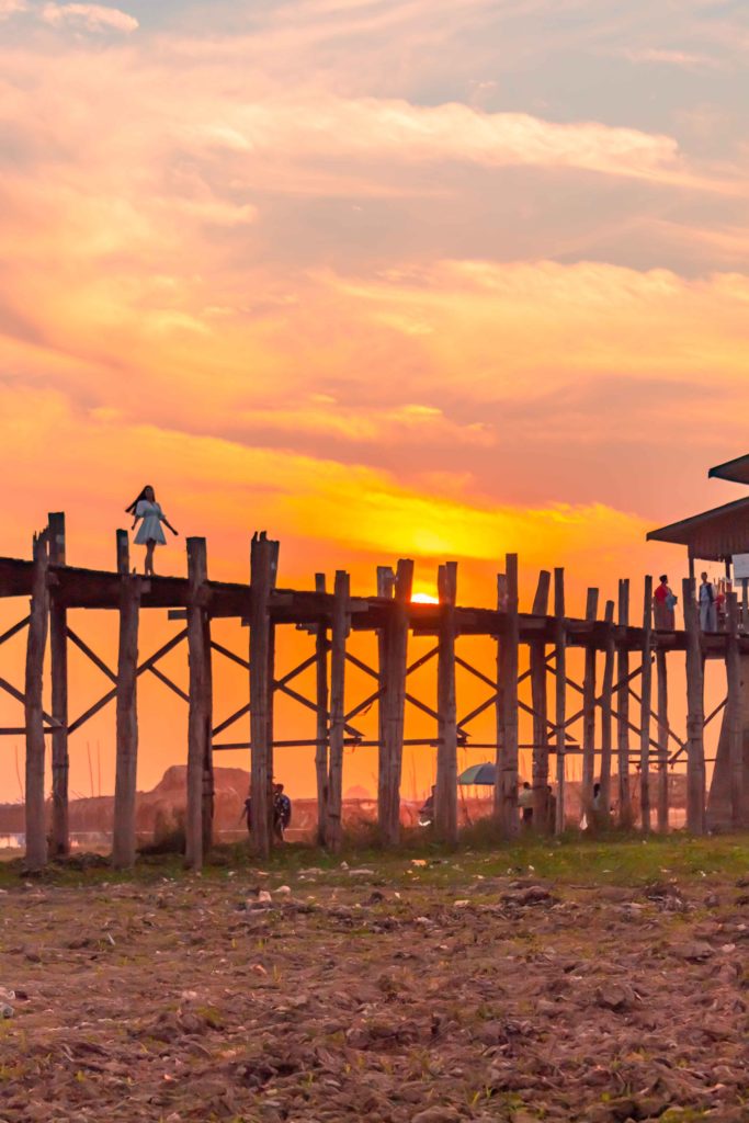 A girl standing on U bein bridge at sunset