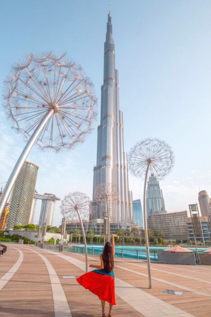 A girl looking at Burj Khalifa and dandelion figures at Burj park