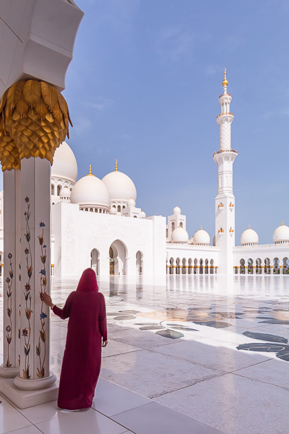 A girl in Abaya looking at Sheikh Zayed Grand Mosque which is one of the most Instagrammable places in Abu Dhabi