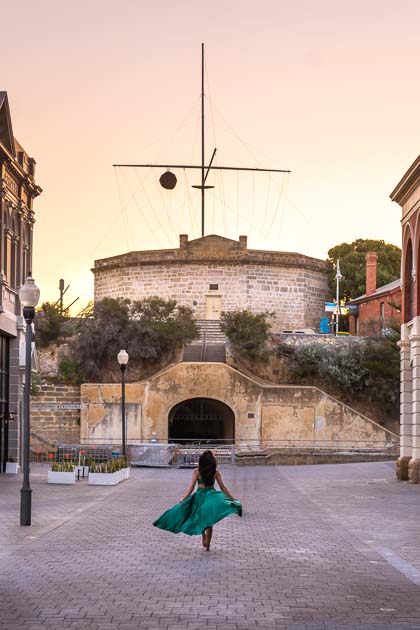 A girl running towards the stunning round house in fremantle australia