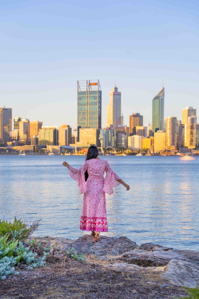 A girl in Pink Dress staring at Perth Skyline with views of swan river