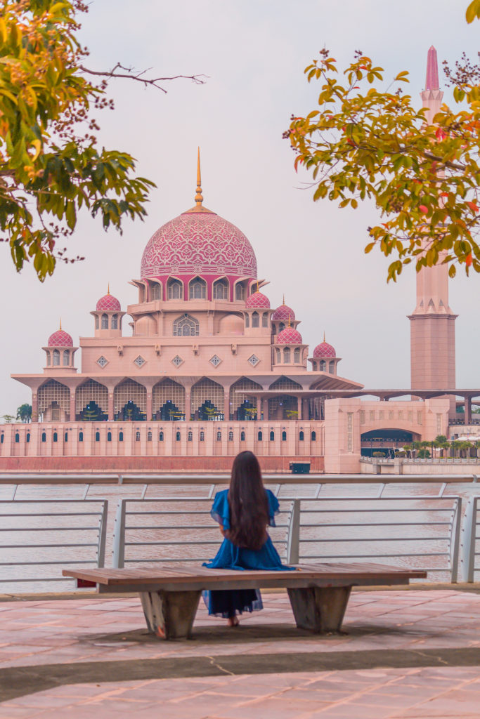 A girl in blue dress staring at Putra mosque aka pink mosque in kuala lumpur in malaysia