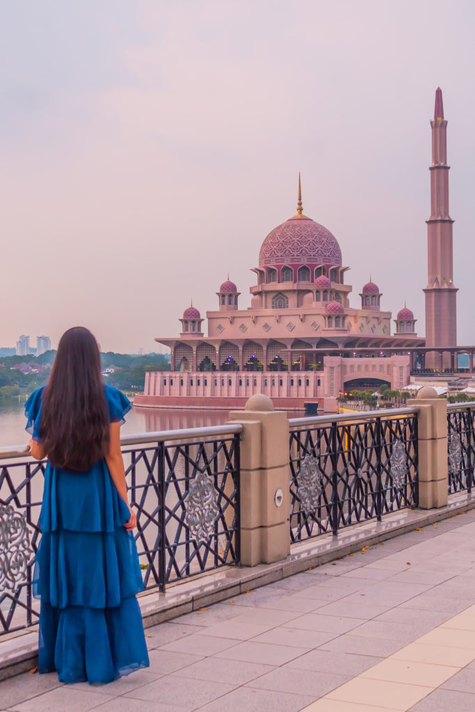 A girl in blue dress staring at Putra mosque aka pink mosque in kuala lumpur in malaysia