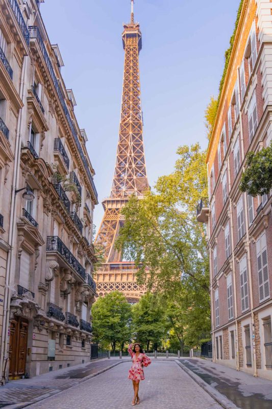 A girl in a short dress on a street with the view of the Eiffel tower